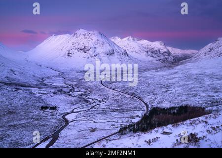 Longue route sinueuse menant à Glencoe avec beau lever de soleil d'hiver. Scottish Highlands, Royaume-Uni. Banque D'Images