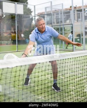 Homme sportif senior jouant au padel sur un court de tennis ouvert Banque D'Images