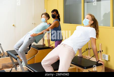 Adolescents dans les masques d'entraînement pilates dans la salle de gym avec traine Banque D'Images