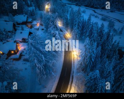 Vue aérienne de la route en ville dans la neige, la forêt, les maisons la nuit Banque D'Images