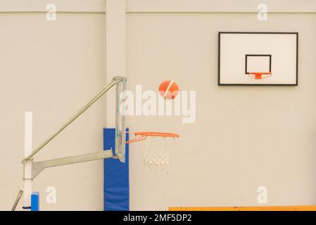 vue latérale d'un basket-ball entrant dans un mini-panier de basket-ball sur un terrain sans parquet, couleur verte Banque D'Images