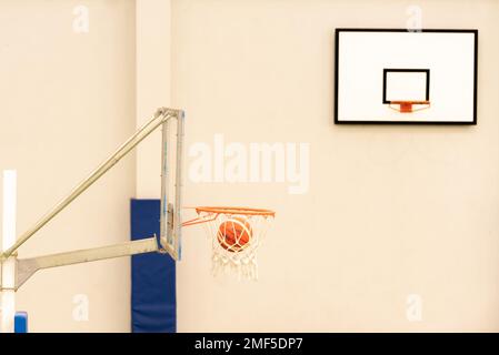 vue latérale d'un basket-ball entrant dans un mini-panier de basket-ball sur un terrain sans parquet, couleur verte Banque D'Images