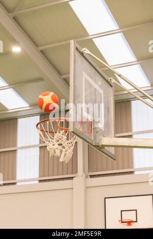 vue latérale d'un basket-ball entrant dans un mini-panier de basket-ball sur un terrain sans parquet, couleur verte Banque D'Images