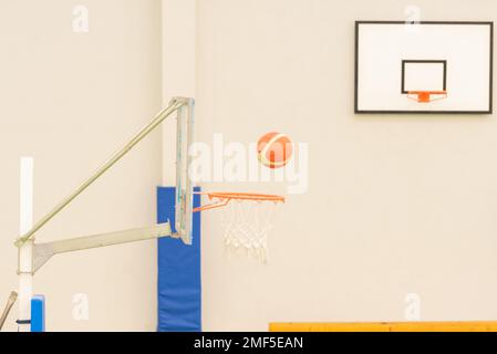 vue latérale d'un basket-ball entrant dans un mini-panier de basket-ball sur un terrain sans parquet, couleur verte Banque D'Images