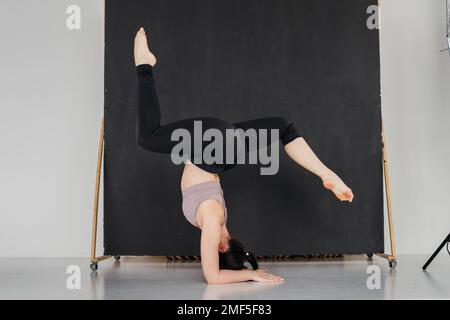 Jeune femme de gymnaste professionnelle debout sur des fractionnements. Jolie fille brunette faisant un support de coude. Une athlète féminine s'échauffe avant de s'entraîner. Station santé Copy Banque D'Images