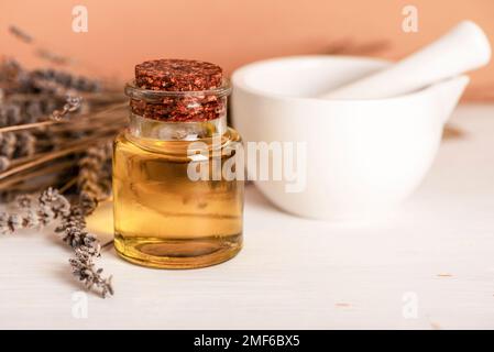 Huile cosmétique naturelle, mortier en céramique blanche et pilon et fleurs séchées à la lavande sur table blanche. Cosmétiques naturels, soins de la peau, aromathérapie et beauté Banque D'Images