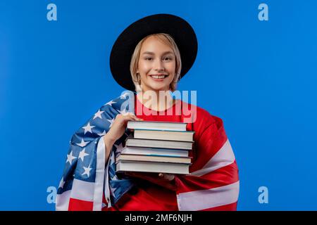 Femme américaine étudiante avec pile de livres sur fond bleu. L'éducation aux États-Unis. Banque D'Images