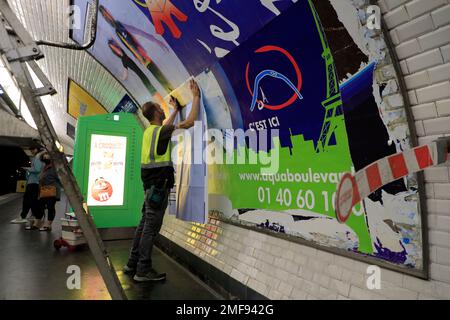 Un travailleur qui pose une affiche publicitaire commerciale sur le mur à l'intérieur d'une station de métro Paris.Paris.France Banque D'Images