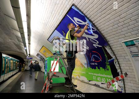 Un travailleur qui pose une affiche publicitaire commerciale sur le mur à l'intérieur d'une station de métro Paris.Paris.France Banque D'Images