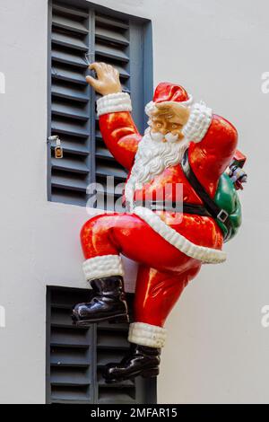Le Père Noël grimpant par les fenêtres Banque D'Images