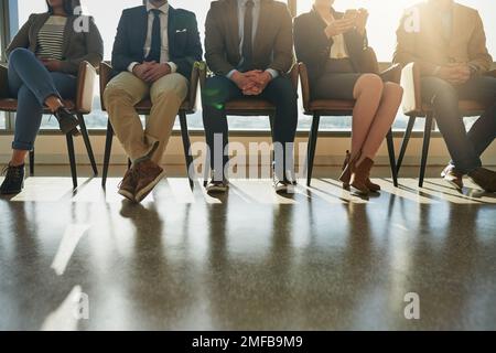 Tous ici pour la même position. un groupe d'hommes d'affaires méconnus assis en file d'attente pour être interviewés. Banque D'Images
