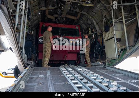 ÉTATS-UNIS Des aviateurs du 75th e Escadron de transport aérien expéditionnaire et du 726th e Escadron de la base aérienne expéditionnaire chargent un camion d'incendie remis à neuf sur un Hercules C-130 sur la ligne de vol du Camp Lemonnier, à Djibouti, le 18 août 2022. Avec la livraison des trois camions d'incendie, le centre de récupération du personnel peut étendre sa portée pour aider plus de personnes dans la région. (Photo des États-Unis Air Force SSgt Branden Rae) Banque D'Images