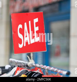 Affiche avec l'inscription Vente de vêtements à prix réduit sur offre spéciale devant un magasin Banque D'Images