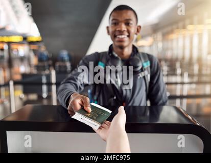 Presque prêt à embarquer. Portrait court d'un beau jeune homme qui remet son passeport et sa carte d'embarquement dans un aéroport. Banque D'Images