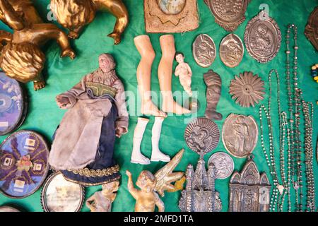 Vieux objets de collection, reliques catholiques, icônes à vendre à un vendeur de rue dans le quartier Centro Historico. Y compris les pieds de poupée, les médaillons. À Naples, Banque D'Images