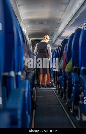 L'hôtesse sert des rafraîchissements à bord de l'avion. Vue sur le couloir de l'avion. Banque D'Images