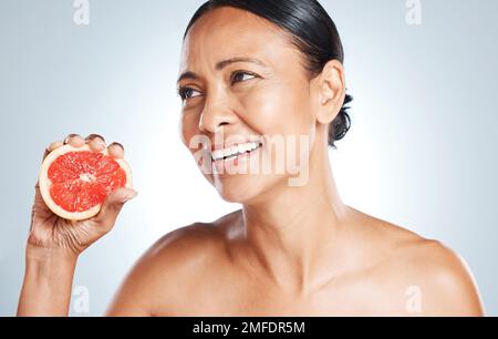 Pamplemousse, soin de la peau et femme sur fond de studio pour des avantages de bien-être. Modèle de beauté, visage et agrumes pour les cosmétiques naturels, détox et Banque D'Images