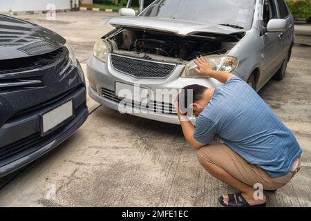 Un homme s'est fâché et s'est assis sur un automobiliste en collision pour une fraude d'assurance-collision se trouvant hors de la voiture Banque D'Images