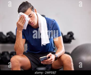 Sueur, fatigué et homme se reposant dans la salle de gym après une séance d'entraînement intense, entraînement sportif. Le fitness, le sport et le réseautage des athlètes masculins sur les médias sociaux Banque D'Images