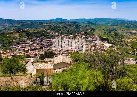 Vue aérienne sur la ville d'Agira, entourée par un paysage agricole avec des collines verdoyantes, des arbres et des champs. Banque D'Images