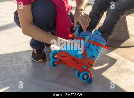 gros plan d'une femme mettant des patins à roulettes sur un enfant Banque D'Images