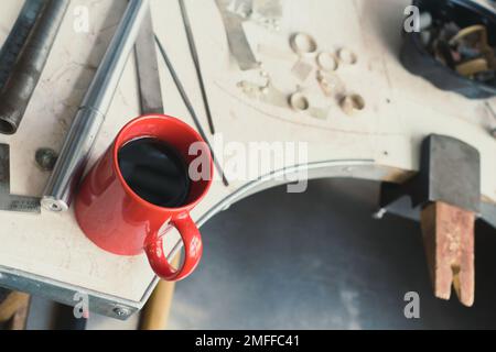 Gros plan sur une tasse rouge avec café placé sur la photo de concept de table d'atelier Banque D'Images