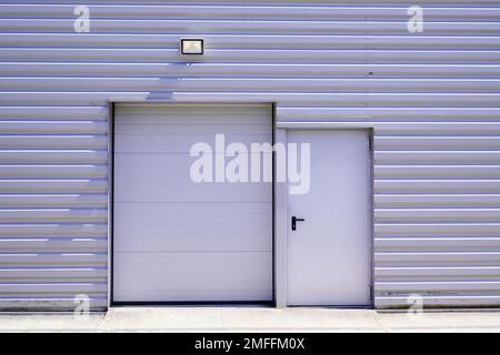 volets roulants d'entrée sur la porte de sortie de secours grise du bâtiment dans l'unité industrielle commerciale Banque D'Images