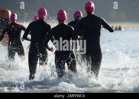 Groupe de participants de triathlon courant dans l'eau pour la partie de natation de la course, des éclaboussures d'eau et des athlètes de course à pied Banque D'Images