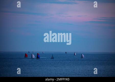 Groupe de bateaux et yachts dans la mer avec voiles pendant le crépuscule Banque D'Images