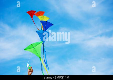 Gros plan d'une main tenant un groupe de cerfs-volants sur un ciel bleu Banque D'Images