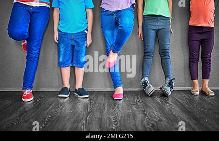 Là où les enfants s'amusent. Court studio photo d'un groupe d'enfants debout contre un mur gris. Banque D'Images