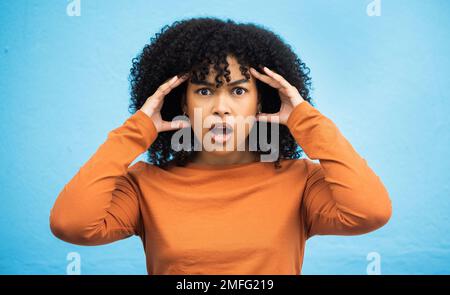 Wow, surprise et portrait avec une femme noire en état de choc debout sur un fond bleu en studio. OMG, confondu et face à une jeune femme attrayante Banque D'Images