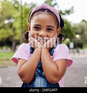 Jolie petite fille, visage et portrait sourire dans une adorable rose décontracté avec le denim au parc extérieur. Joyeux enfant de petite taille souriant dans le bonheur avec Banque D'Images