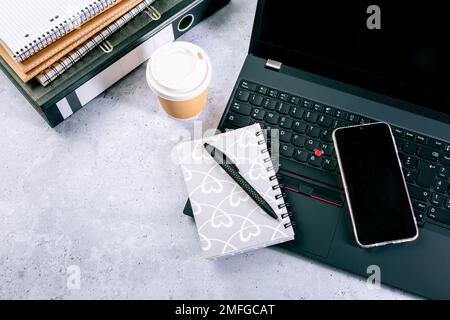 Vue de dessus du bureau d'ordinateur avec clavier, smartphone, papeterie et tasse à café Banque D'Images