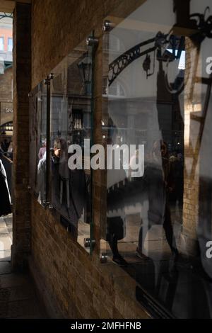 Londres - 02 27 2022 : exposition de peintures représentant le marché de Covent Garden en 1960s avec des réflexions de passants Banque D'Images