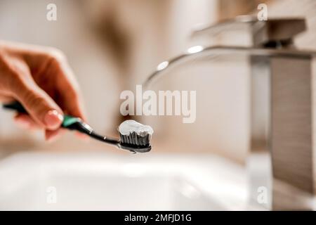 Main de fille tenant brosse à dents avec pâte sous l'eau courante Banque D'Images