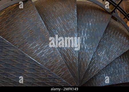 Motif sur un escalier métallique noir autour du poteau métallique. Banque D'Images