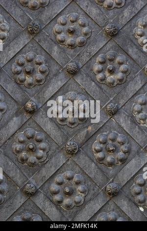 Une vieille porte en métal, des portails forgés, des rivets sur la façade d'une porte en fonte, une poignée ronde pour ouvrir la porte, la texture de la vieille fonte. Phot de haute qualité Banque D'Images