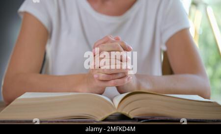 Une femme lit un livre épais et prie en gros plan. Banque D'Images