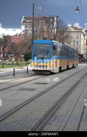 Une photo verticale d'un tramway passant par une rue étroite avec des bâtiments dans le centre-ville, scène de rue Banque D'Images