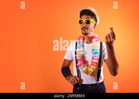 Déguisement brésilien de carnaval. Black Man with Carnival Costume Amaning Fun, isolé sur fond orange Banque D'Images