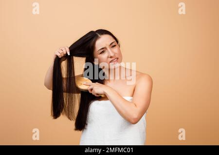 Une jeune femme indienne malheureuse peignant ses cheveux emmêlés avec la brosse Bamboo Banque D'Images