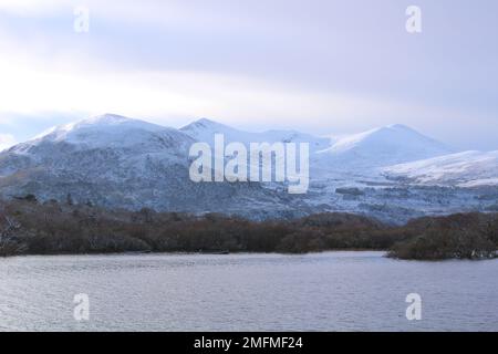 La neige couvrait les ruisseaux McGillycuddy, la plus haute chaîne de montagnes d'Irlande, avec Lough Leane. Killarney chaîne de montagnes hiver paysage économiseur d'écran papier peint. Banque D'Images