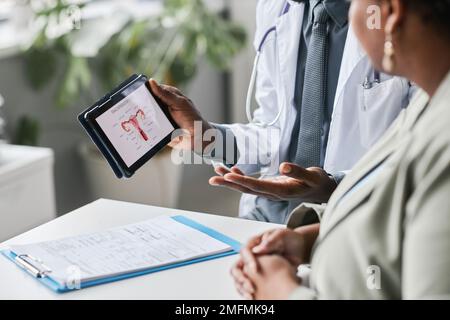 Gros plan du médecin tenant le comprimé avec les graphiques de santé reproductive des femmes Banque D'Images