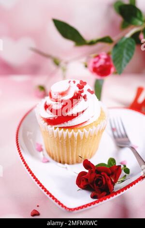 Saint-Valentin tourbillons de cupcake avec glaçage blanc rouge et roses | fond de dessert de jour de Saint-Valentin, foyer sélectif Banque D'Images