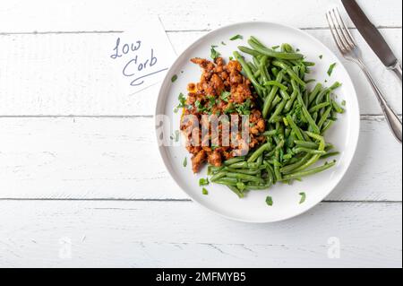 Dîner ou déjeuner avec un délicieux ragoût de poulet crémeux et des haricots verts sur une assiette isolée sur fond blanc avec un espace pour le texte. Pose à plat Banque D'Images