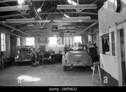 1950s, historique, vue arrière de deux voitures de l'époque garées à l'intérieur du garage à Hargood Motor Sales, Parrs Wood, East Didsbury, Manchester, Angleterre, ROYAUME-UNI. Banque D'Images