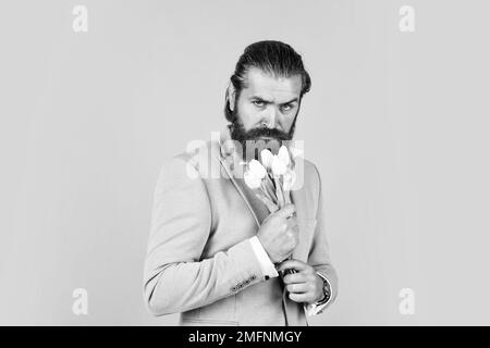 beau homme d'affaires caucasien avec la coiffure tendance en veste avec des fleurs de tulipe, cadeau Banque D'Images