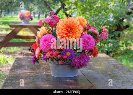 Roses, asters, dahilia en vase dans le jardin sur une table en bois. Jour ensoleillé. Véranda dans le jardin. Banque D'Images