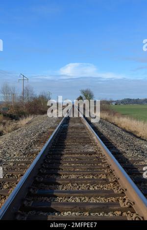 Les lignes de chemin de fer en acier convergent vers le point de fuite le jour du ciel bleu sans personne Banque D'Images